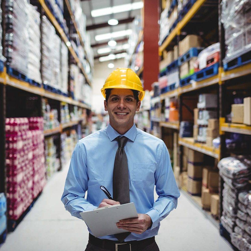 Smiling warehouse manager writing on clipboard in warehouse Smiling warehouse manager writing on clipboard in warehouse