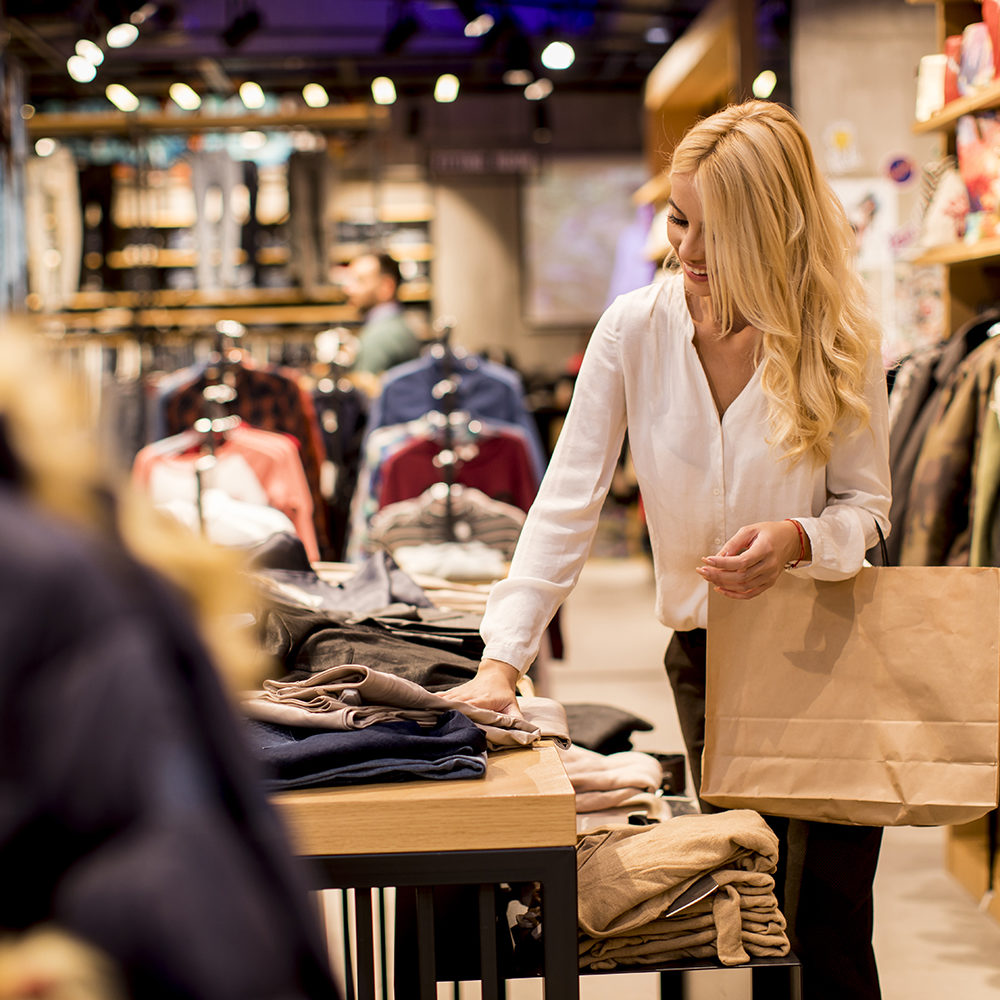 Young woman with shopping bags standing at the clothing store Beautiful young woman with shopping bags standing at the clothing store